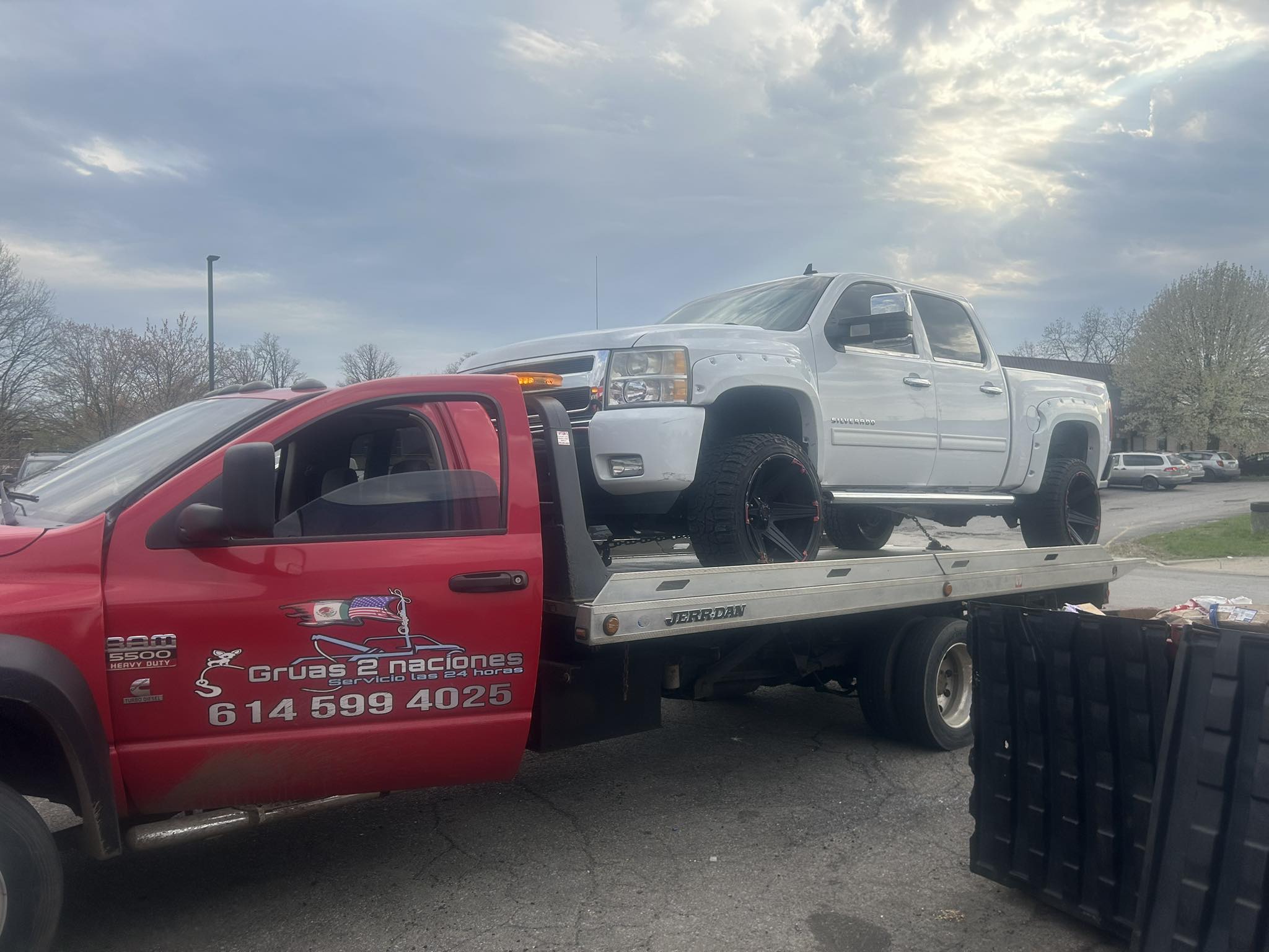 Grúas 2 Naciones flatbed tow truck transporting a lifted Chevrolet Silverado in Columbus, Ohio